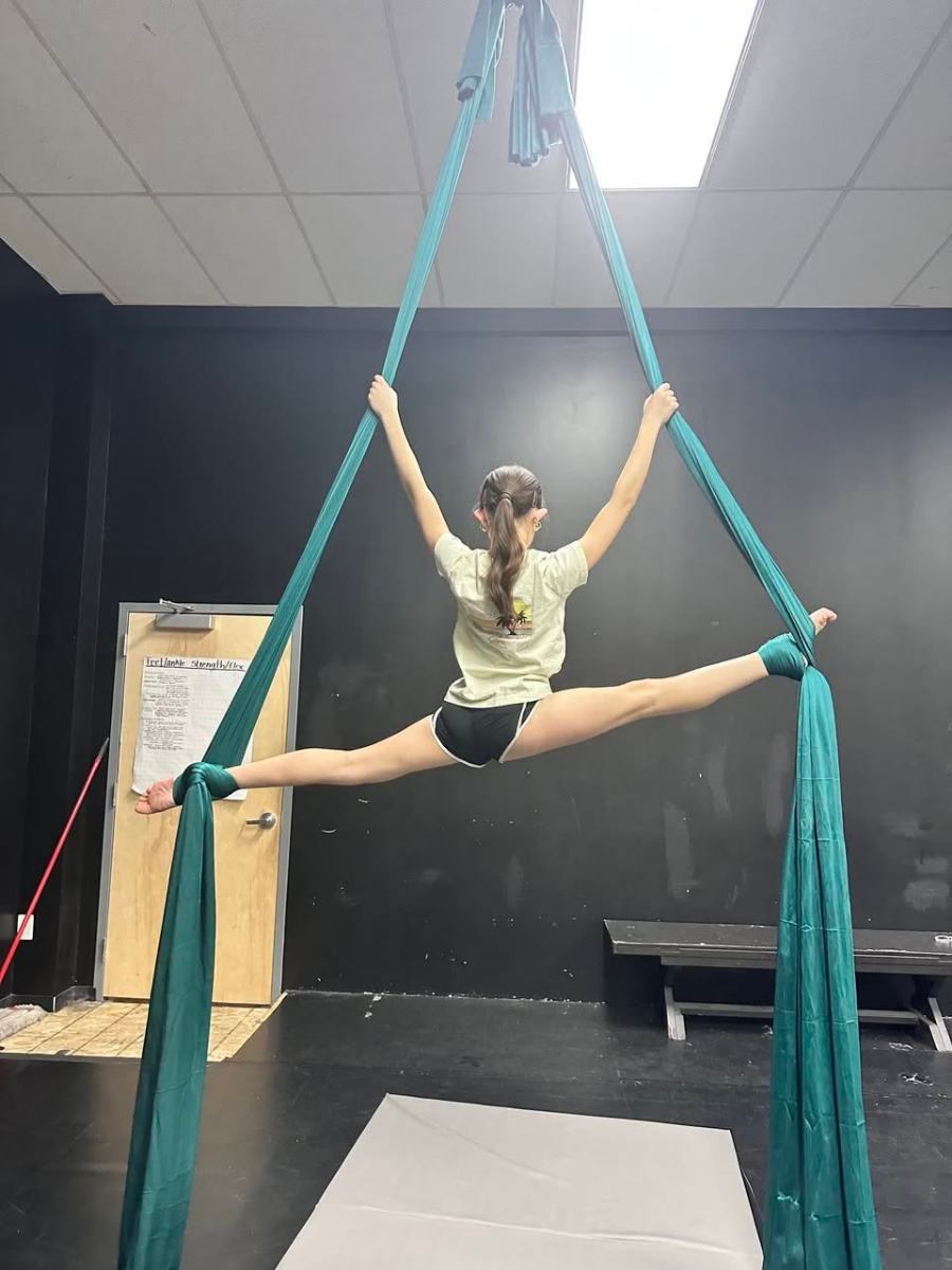A dancer in a full split on the aerial silks